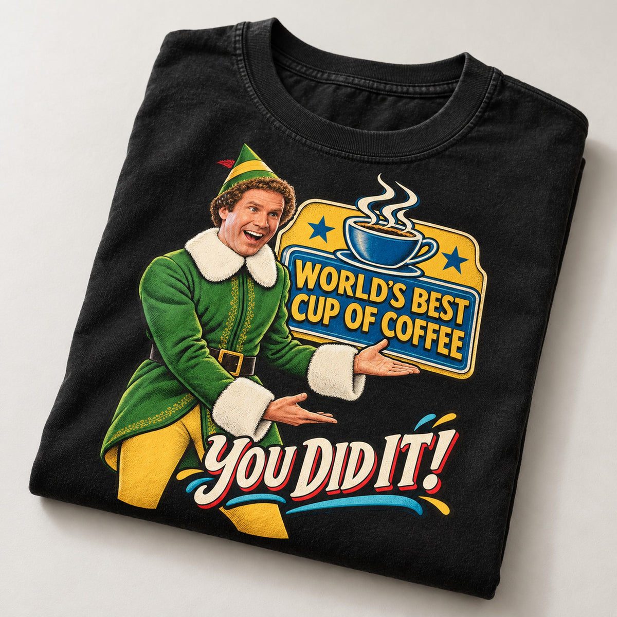World's Best Cup of Coffee Elf Christmas T-Shirt, folded on a warm grey backdrop