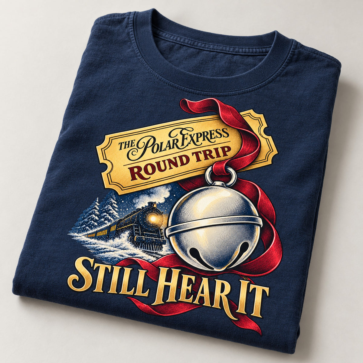 Still Hear It Sleigh Bell Christmas Train T-Shirt, folded on a warm grey backdrop