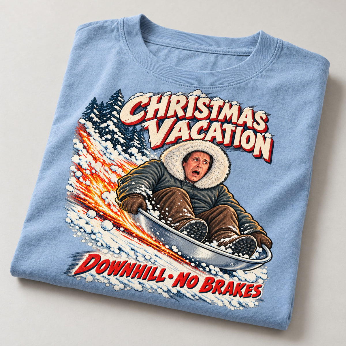 Downhill No Brakes Saucer Sled Christmas T-Shirt, folded on a warm grey backdrop