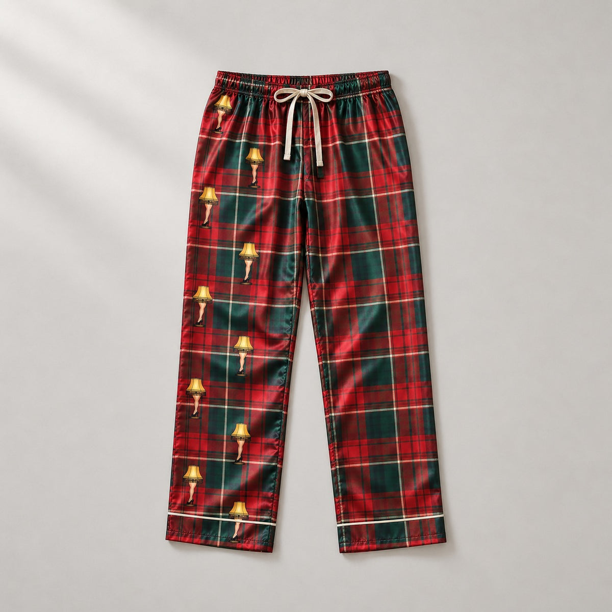 Red and green tartan satin pajama pants with yellow leg lamps, laid flat